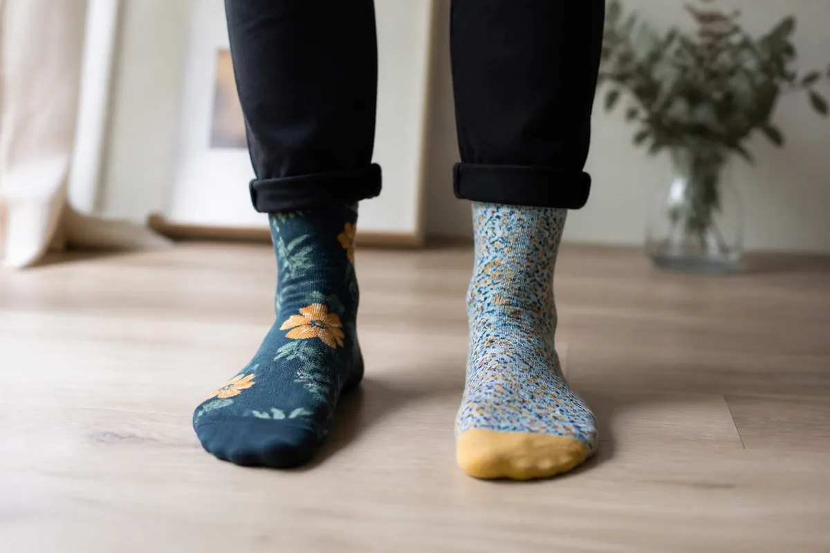 Pieds en chaussettes dépareillées colorées sur un sol en bois clair, ambiance chaleureuse et lumineuse